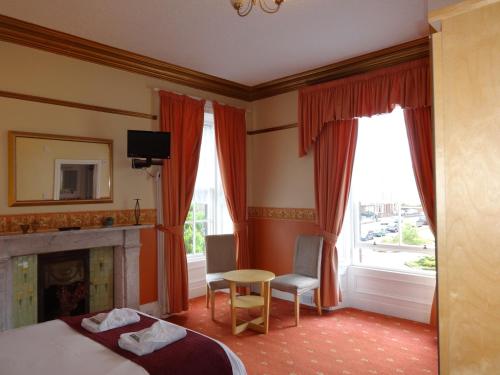 a bedroom with a bed and a table and a fireplace at Dumfries Villa in Dumfries
