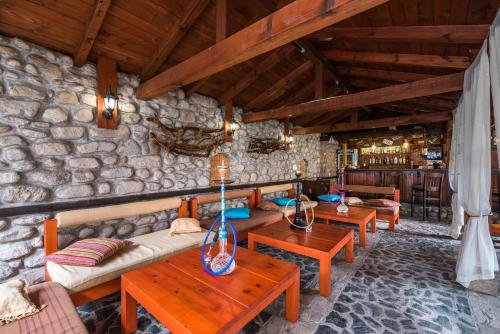 a living room with wooden tables and a stone wall at Hotel Ida in Bansko