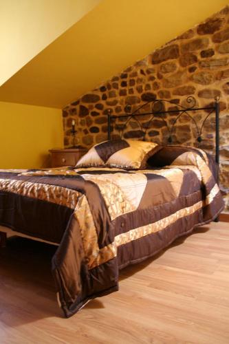 a large bed in a room with a stone wall at Posada El Arrabal in Arenas de Iguña