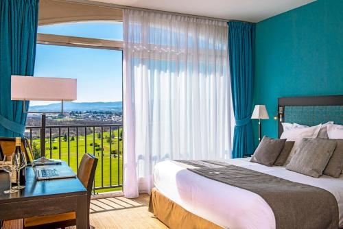 a bedroom with a bed and a desk and a window at Domaine De Saint Clair Spa & Golf in Saint-Clair