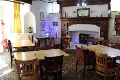 a restaurant with wooden tables and chairs and a fireplace at The Darnley Hotel in Ilfracombe
