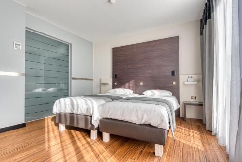 1 Schlafzimmer mit 2 Betten und Holzboden in der Unterkunft Le Merceny Motel in Bastogne