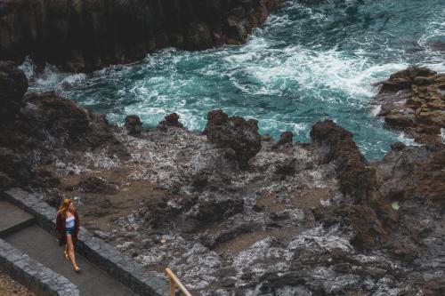 a woman standing on the rocks near the water at Casa Grande Surf Hostel in El Médano