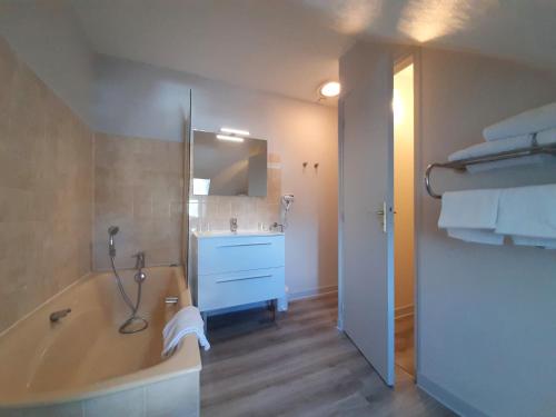 ein Badezimmer mit einer Badewanne, einem Waschbecken und einem Spiegel in der Unterkunft Logis Hôtel Saint Paul in Vivy