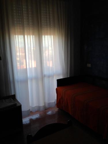 a bedroom with a bed and a window with white curtains at Hotel Viking in Rimini