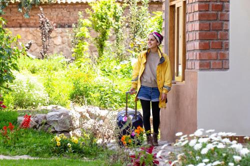 a woman standing in a garden with a suitcase at Allin Illary Eco Hospedaje in Urubamba