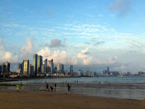 a group of people on a beach with a city in the background at Qingdao Elegant Central Apartment in Qingdao