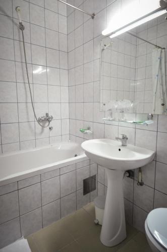 a white bathroom with a sink and a bath tub at Garni Hotel Lake in Čačak