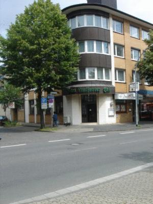 un bâtiment sur le côté d'une rue avec un arbre dans l'établissement Hotel Lintforter Hof, à Kamp-Lintfort