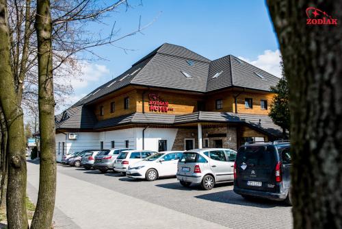 a building with cars parked in a parking lot at Hotel Zodiak in Radomsko
