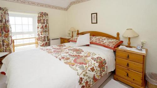 a bedroom with a bed and a dresser and a window at Dinas Cottage in Penrhyndeudreath