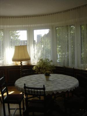 ein Wohnzimmer mit einem Tisch, Stühlen und Fenstern in der Unterkunft Hotel Lintforter Hof in Kamp-Lintfort