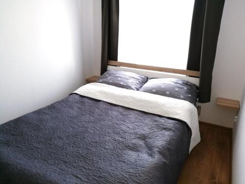 a bed with two pillows in a room with a window at Harbor 9 Apartment in Kołobrzeg