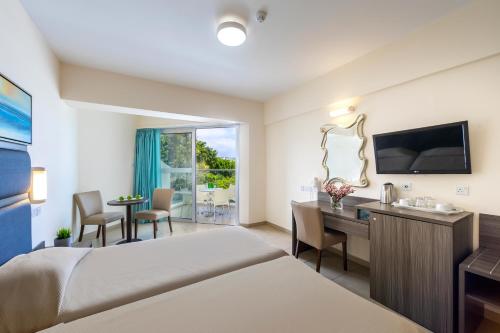 a hotel room with a bed and a desk and a television at Tofinis Hotel in Ayia Napa