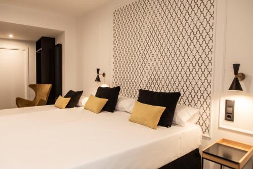 sypialnia z dużym białym łóżkiem z żółtymi poduszkami w obiekcie Blanq Comedias w Walencji