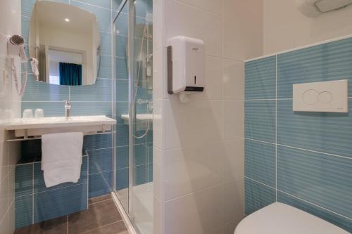 W łazience znajduje się prysznic, toaleta i umywalka. w obiekcie Brit Hotel Hermes w mieście Couchey