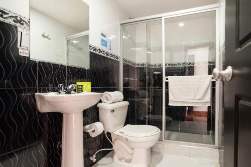 y baño con aseo, lavabo y ducha. en Hotel Dorado 100, en Bogotá