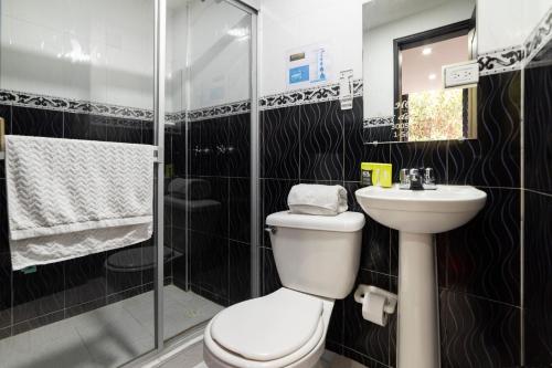 a bathroom with a toilet and a sink and a shower at Hotel Dorado 100 in Bogotá