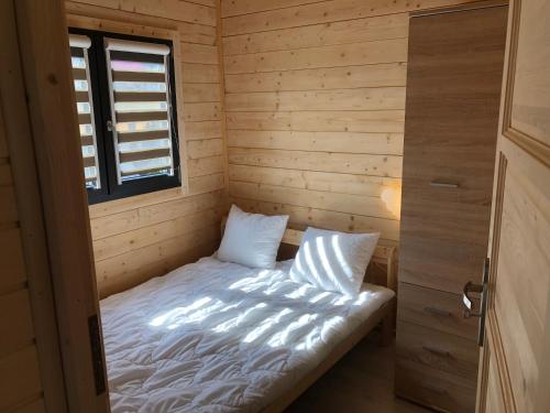 Cette chambre en bois comprend un petit lit et une fenêtre. dans l'établissement Ośrodek Wczasowy Kuba, à Jarosławiec