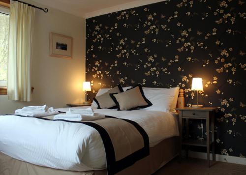 una camera con due letti e una parete nera con fiori di Arivonie Lochside Cottage a Glencoe