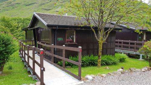 a small building with a wooden fence in front of it at Beech Chalet in Glencoe