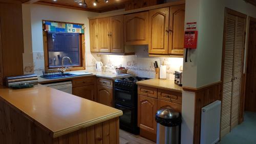 una cocina con armarios de madera y estufa negra en Birch Chalet, en Ballachulish