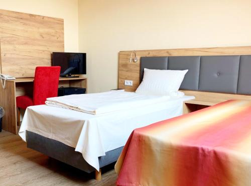 ハーナウ・アム・マインにあるTurm Hotel Hanauのベッドと赤い椅子が備わるホテルルームです。