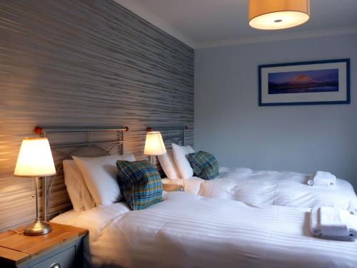 a bedroom with two white beds and a lamp at Cherry Tree Cottage in Glencoe