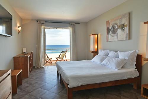 - une chambre avec un lit et une vue sur l'océan dans l'établissement La Florentine, à Saint-Florent