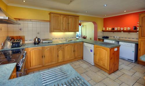 a large kitchen with wooden cabinets and white appliances at Hawthorn Cottage in Glencoe