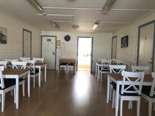 a dining room with wooden tables and white chairs at Klovabo Bed & Breakfast in Hönö
