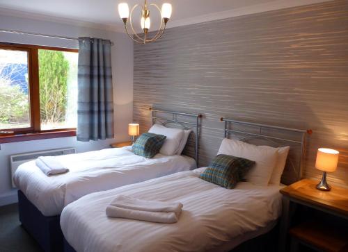 dos camas sentadas una al lado de la otra en una habitación en Holly Tree Cottage, en Glencoe