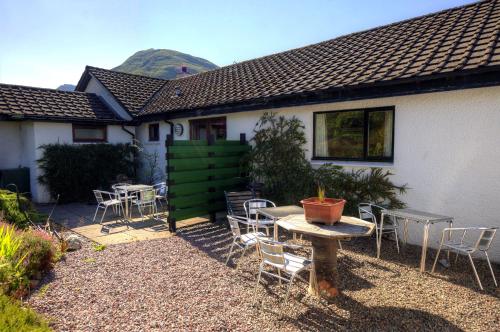 a patio with chairs and tables and a house at Holly Tree Cottage in Glencoe