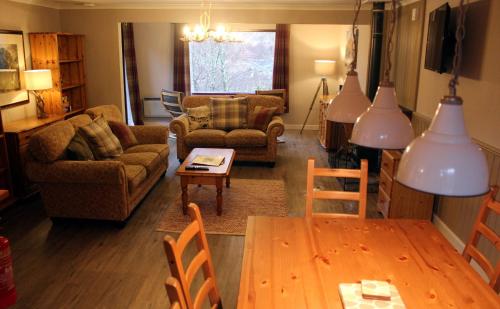 a living room with a couch and a table at Oak Tree Lodge in Ballachulish