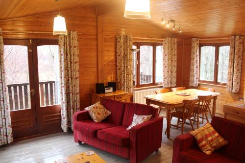 a living room with a red couch and a table at Rowan Tree Lodge in Glencoe