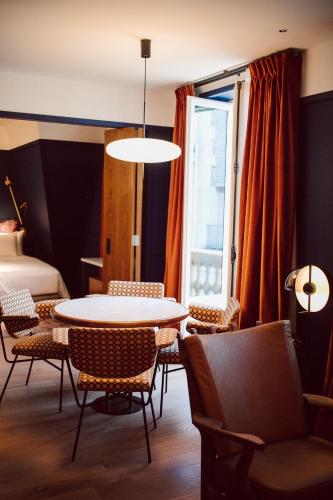 a room with a table and chairs and a bed at Hôtel Le Ballu in Paris
