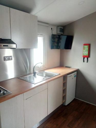 a kitchen with white cabinets and a sink and a window at Mira Lodge Park in Praia de Mira