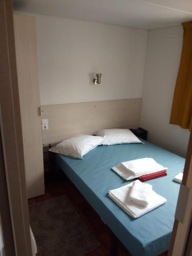 a bed in a room with two towels on it at Mira Lodge Park in Praia de Mira