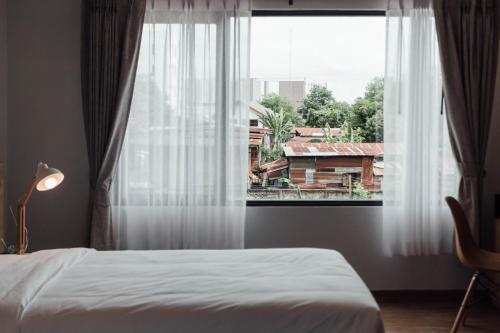 a bedroom with a bed and a large window at Clay Hotel Udonthani in Udon Thani