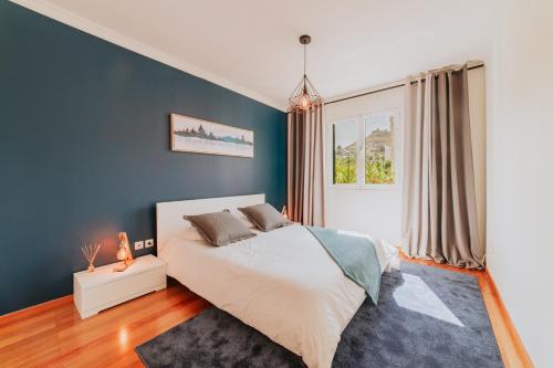 een slaapkamer met een groot bed en een blauwe muur bij Funchal Lounge Apartment II in Funchal