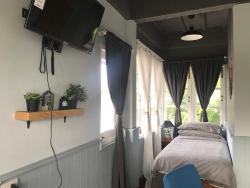 a bedroom with a bed and a tv on the wall at P.O.E Posh Homestay in Cha Am