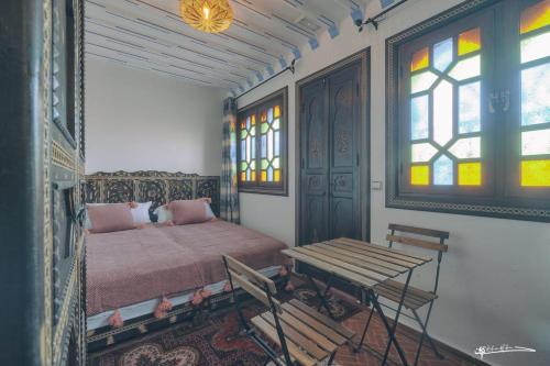 una camera con letto, tavolo e finestre di Dar Rafik a Chefchaouen