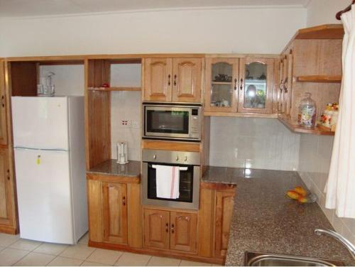 a kitchen with wooden cabinets and a white refrigerator at Rowsvilla Guest House in Beau Vallon