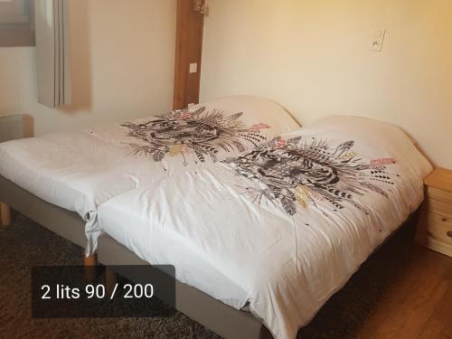 a bedroom with a bed with a white comforter at Chaleureux 2 pièces avec terrasse à Seez in Séez