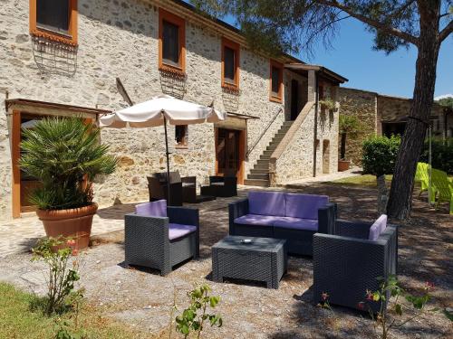 a patio with purple chairs and an umbrella at Tenuta Di Maro in Sticciano