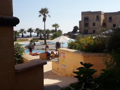 Eine Frau steht neben einem Pool mit einer Palme in der Unterkunft Poolside Luxury Apartment with Patio 11A4S in Mġarr