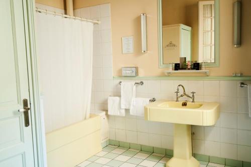 La salle de bains blanche est pourvue d'un lavabo et d'une douche. dans l'établissement Hôtel Langlois, à Paris