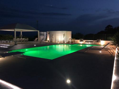 a swimming pool at night with green illumination at GIGLIO DI MARE Residence in Sellia Marina