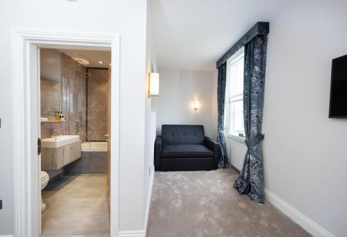 uma casa de banho com uma cadeira preta e uma janela em The Kings Arms em Kingston upon Thames