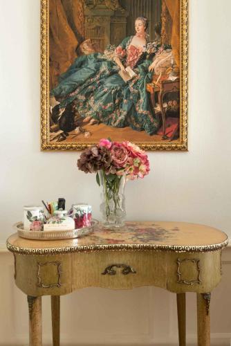 a table with a vase of flowers and a painting at Maison d'hôtes de charme La Rose de Ducey près du Mont Saint Michel in Ducey